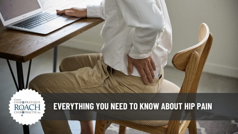 a person sitting at a desk holding their hip in pain.