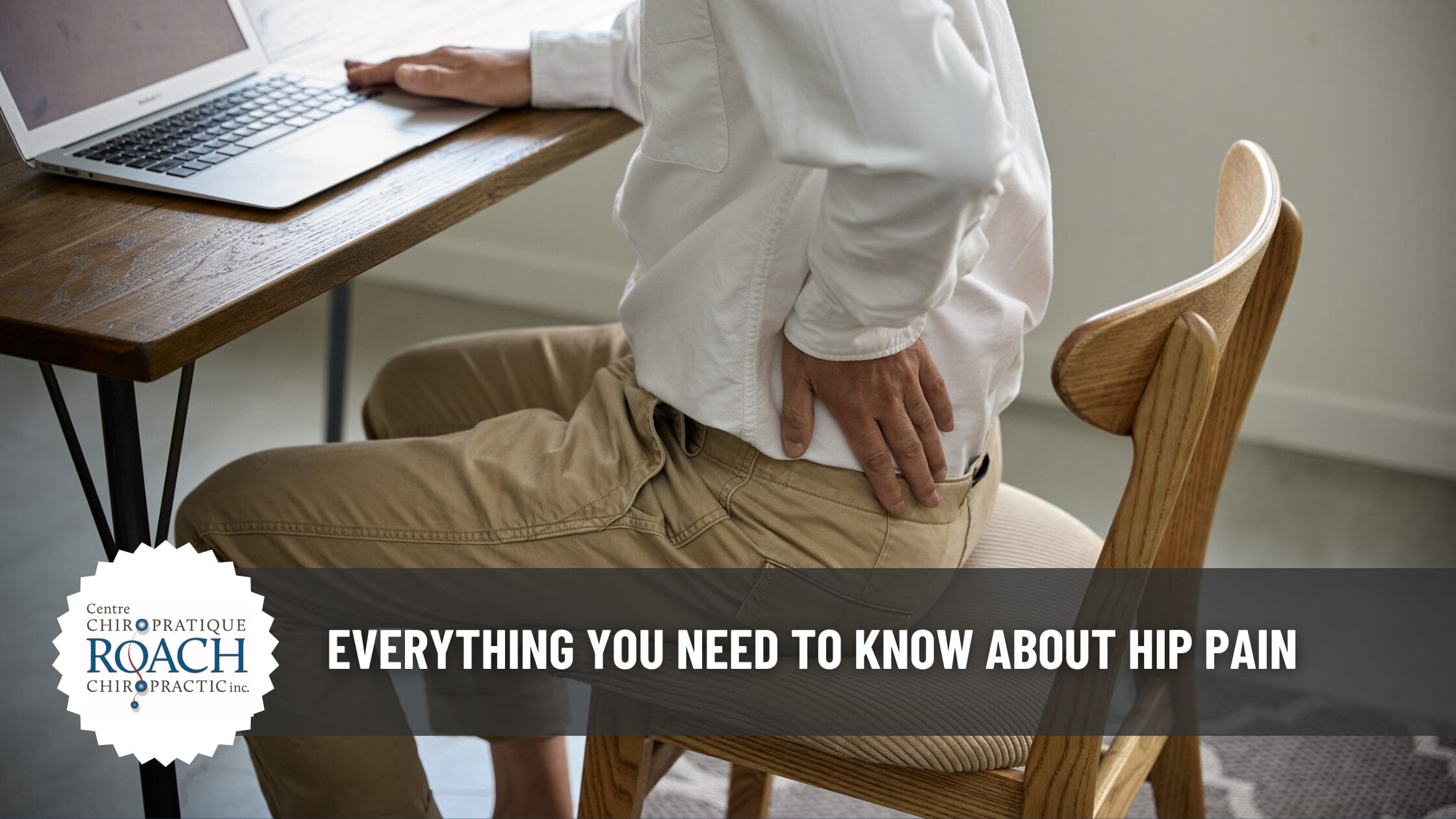 a person sitting at a desk holding their hip in pain.