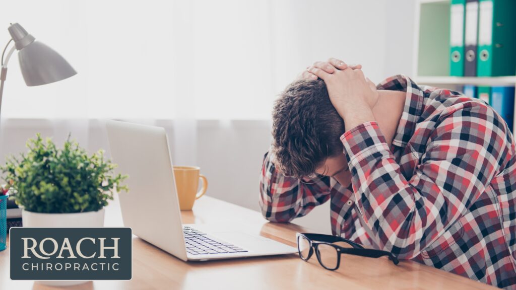 Chiropractic Treatment For Migraine Relief 5 A man at his desk with a headache